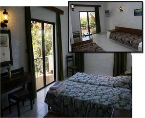 A bedroom with a bed, a desk, and a chair. There is a balcony with a view of greenery. - Oasis Hotel Bungalows Rodos  (Rhodes)