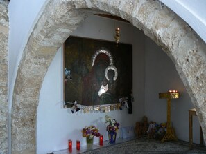 A chapel with a stone archway, a religious icon, candles, flowers, and a golden candelabra. - Oasis Hotel Bungalows Rodos  (Rhodes)