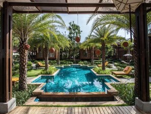 A pool area with a clear blue pool, surrounded by palm trees and lounge chairs. - The Cottage Aonang (Krabi)