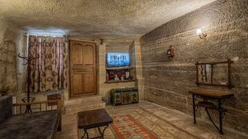 A cozy room with a wooden door, a television, a small table, and a patterned rug.