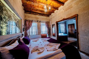 Un cuarto acogedor con techo de madera, una cama grande con almohada morada y un espejo que refleja un baño.