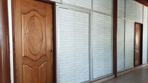 A hallway with wooden doors and white brick-patterned walls. - Horizon Inn (Pangkor Island)