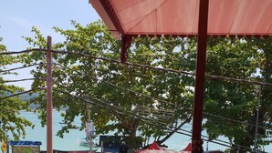 A wooden deck with a railing, overlooking a beach area with a parked van and a motorcycle. - Horizon Inn (Pangkor Island)