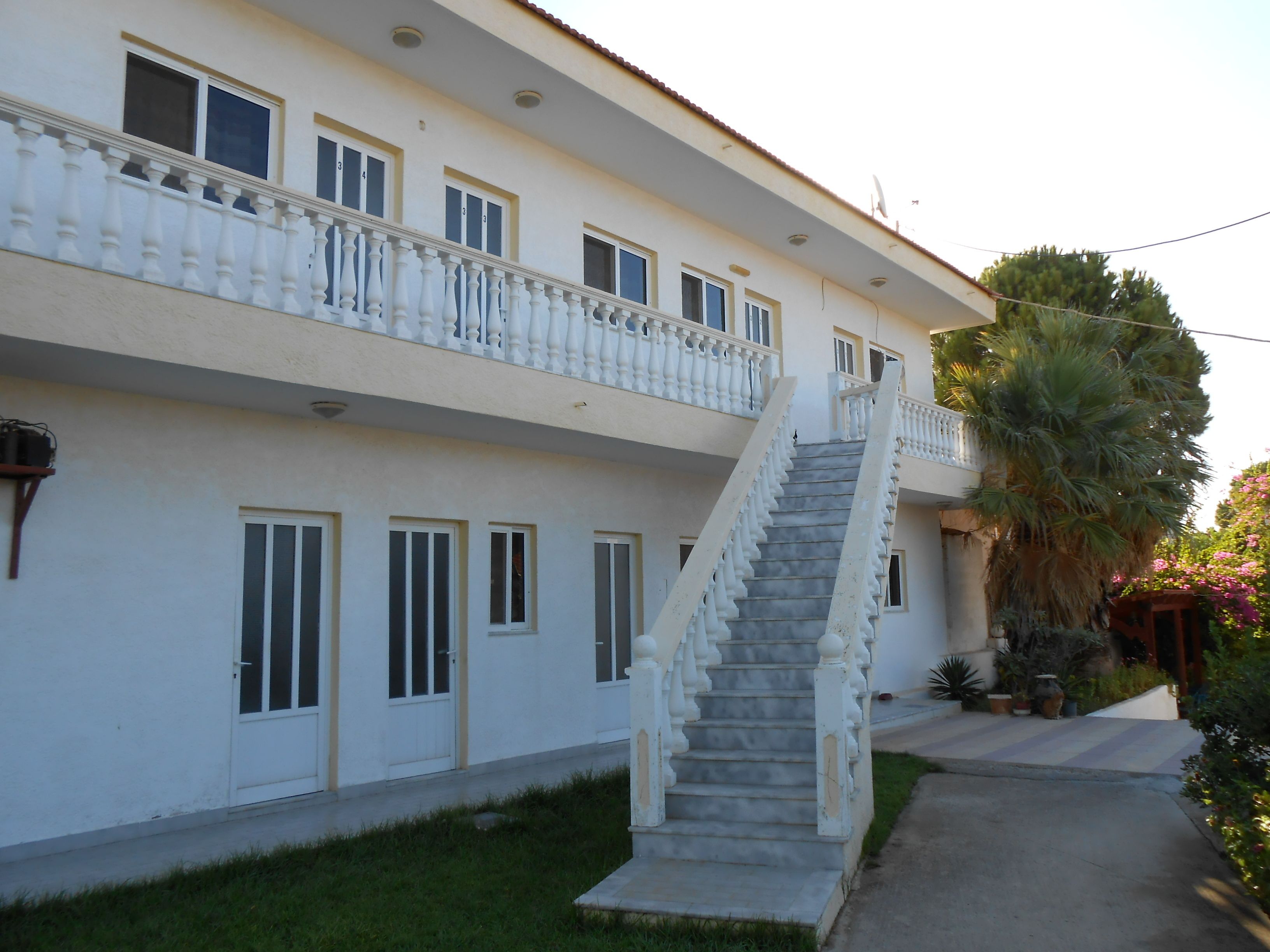 A two-story building with a central staircase, white exterior, and multiple windows.
