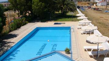 Alberca al aire libre, sombrillas en la alberca y camastros