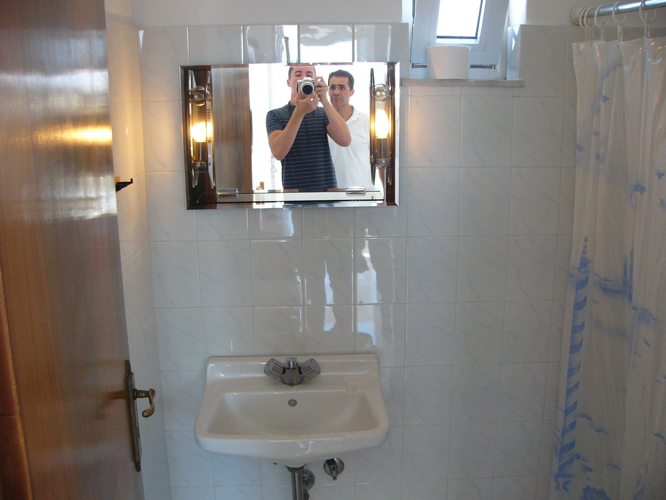 Un baño con lavamanos, espejo y cortina de ducha.