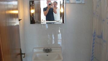 Un baño con lavamanos, espejo y cortina de ducha.