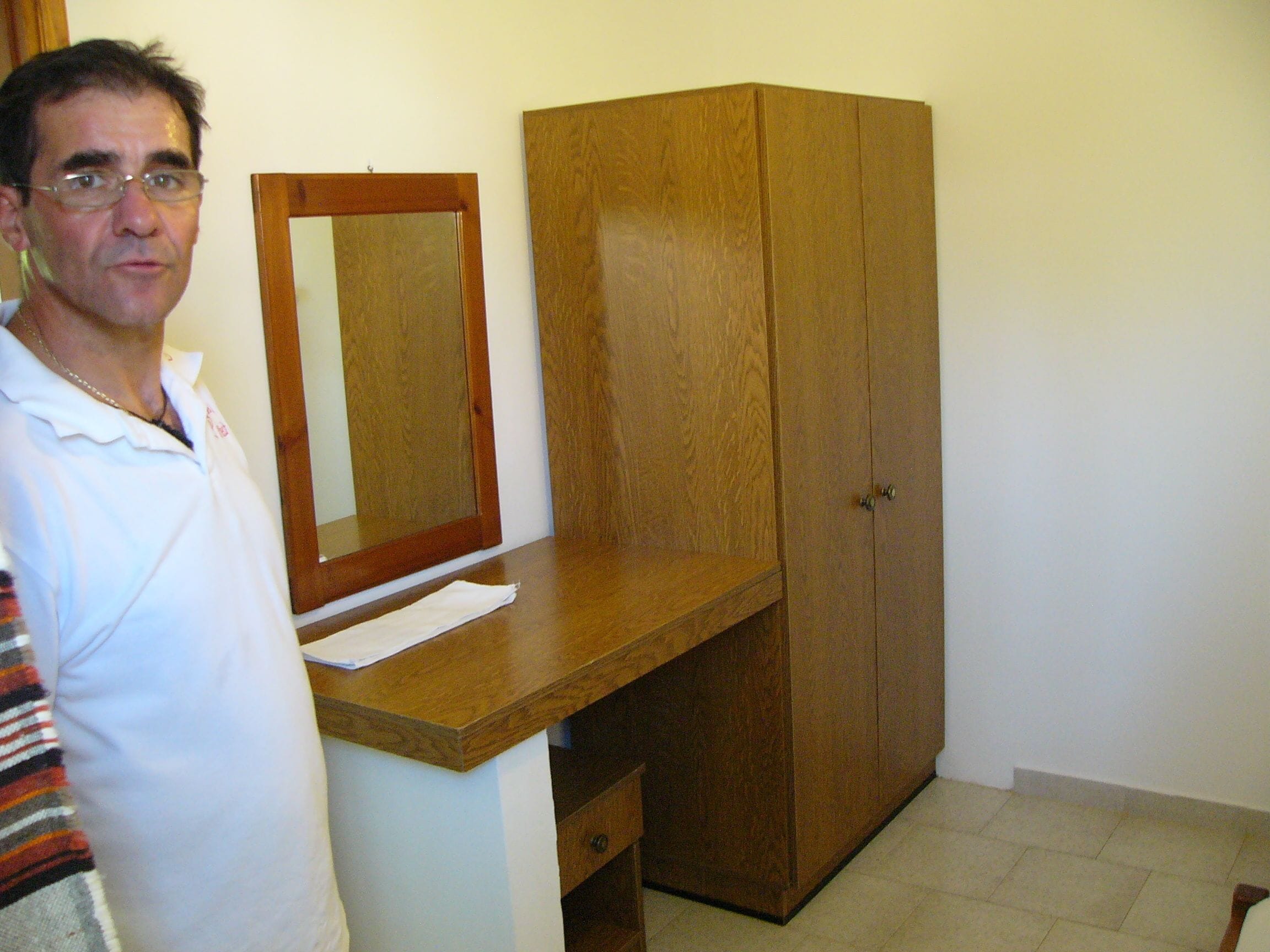 A room with a wooden desk, a mirror, and a wardrobe.