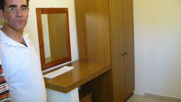 Une pièce avec un bureau en bois, un miroir et une armoire.