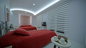 A hotel room with two beds, a television, a small table with cups and a basket, and a patterned wall. - Cappadocia Symbol Hotel (Nevsehir)