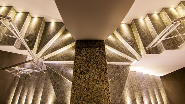 A spiral staircase with granite steps and metal railings, leading to a landing area with a central column. - Cappadocia Symbol Hotel (Nevsehir)