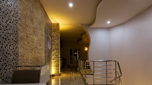 A hallway with a stone wall, a metal railing, and a staircase. - Cappadocia Symbol Hotel (Nevsehir)