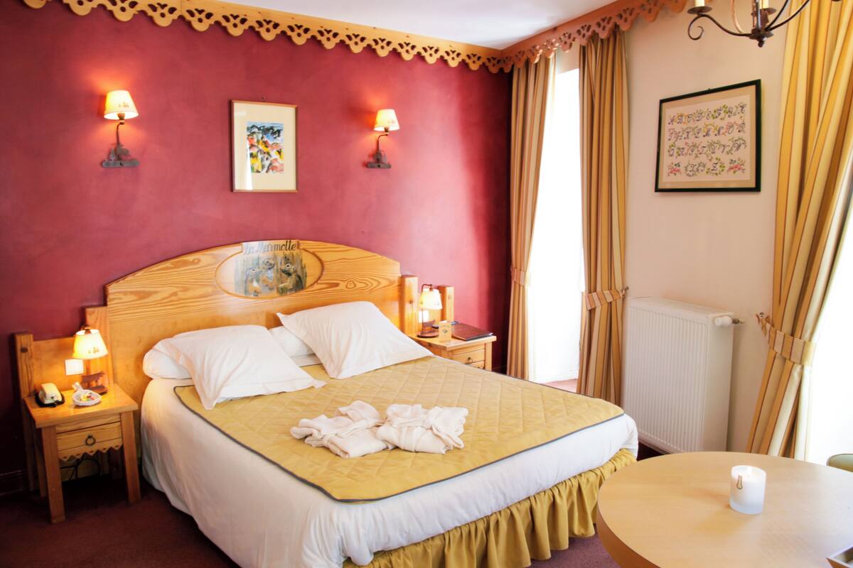 Une chambre d’hôtel avec un lit, deux lampes de chevet, une table avec une bougie et un tableau encadré au mur.