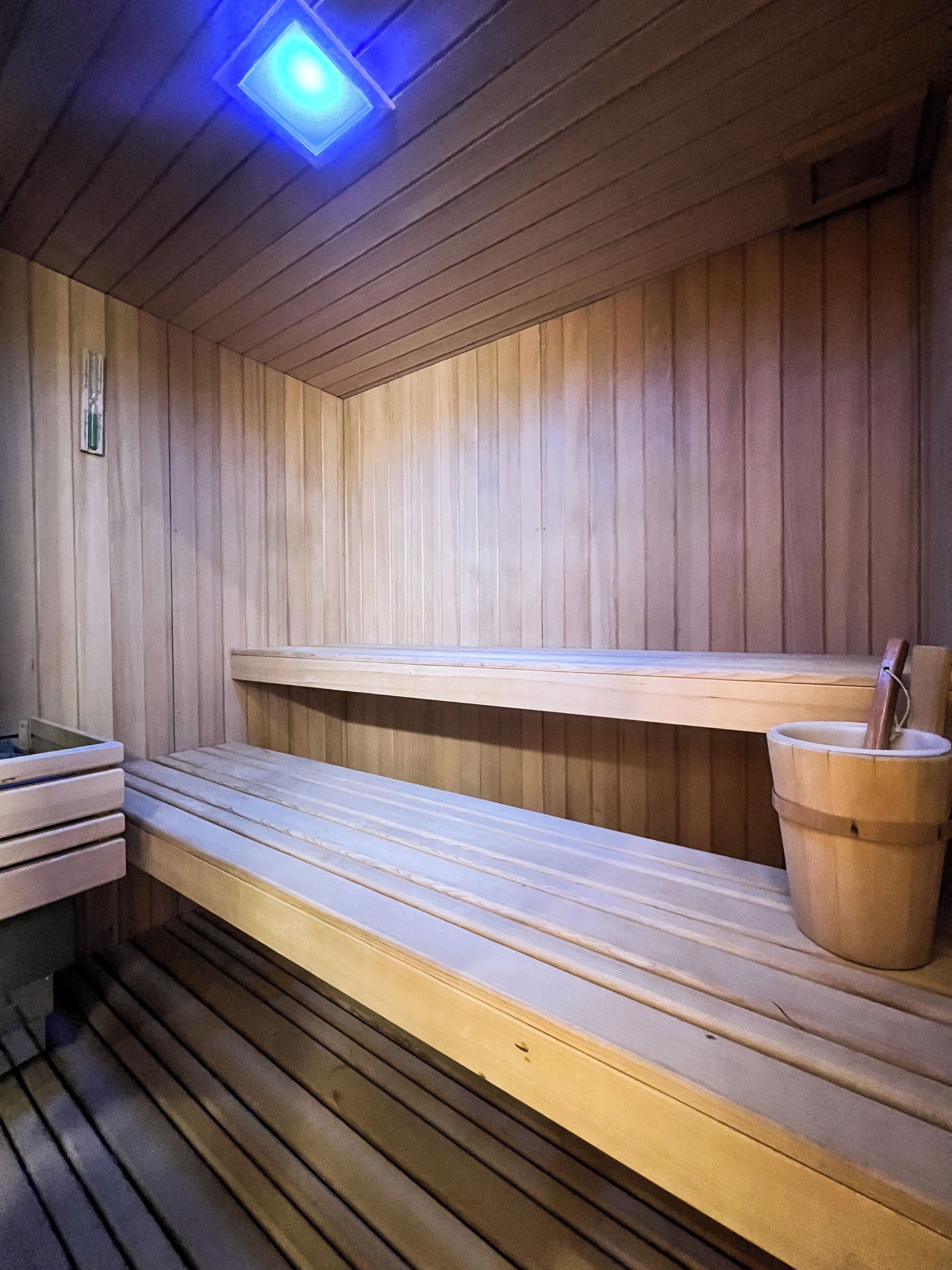 A sauna with wooden benches and a bucket.