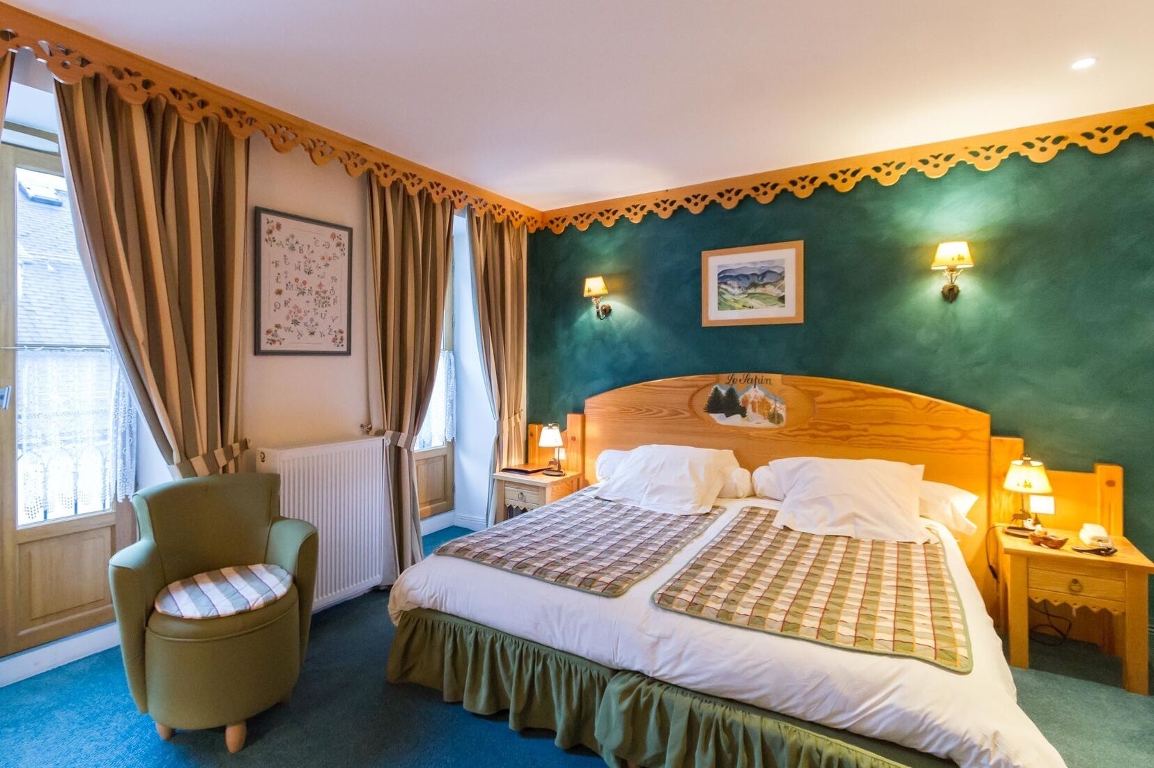 Une chambre d’hôtel avec un grand lit, une chaise, deux tables de chevet avec des lampes, un radiateur et une fenêtre avec des rideaux.