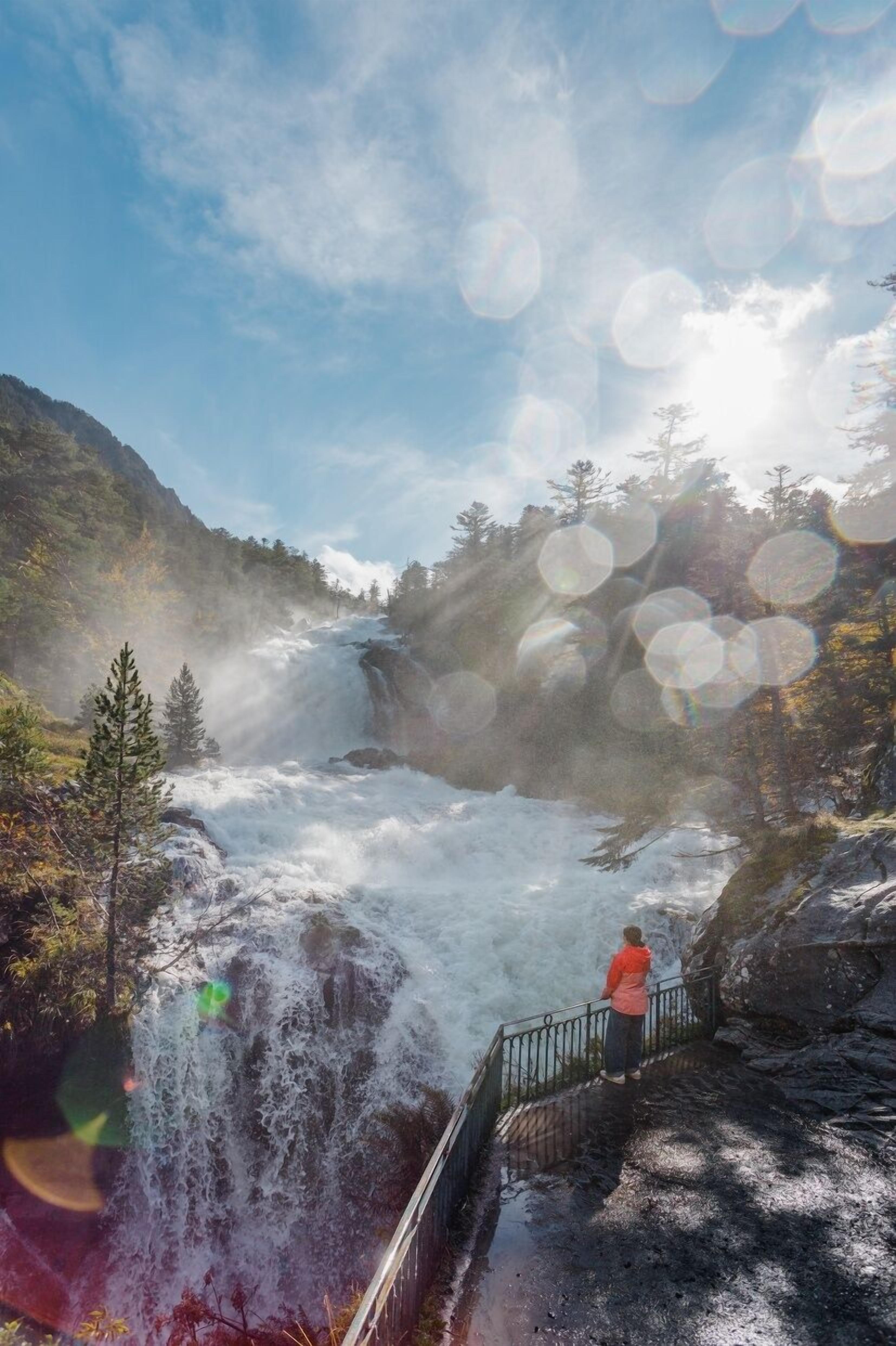 Una cascada con una persona de pie en una plataforma de observación.