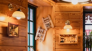 Interior de madera con una escalera de madera, un estante con objetos pequeños y una lámpara.