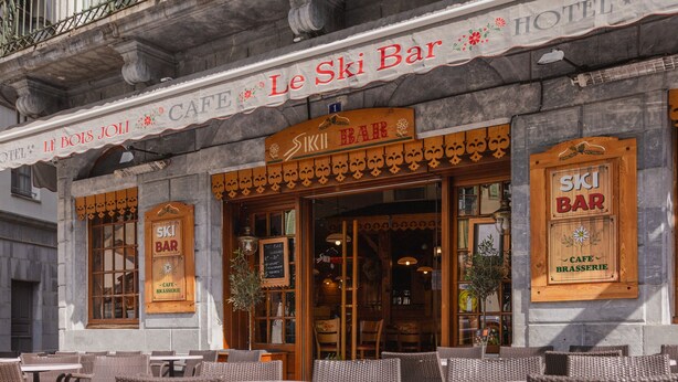 Un hotel con mesas al aire libre y un letrero que dice "Le Ski Bar".