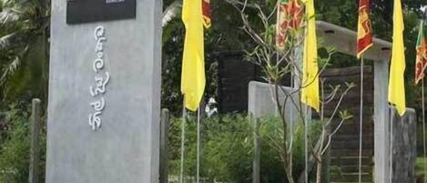 Un monument commémoratif orné d’inscriptions et d’une photographie, entouré de drapeaux et de verdure.