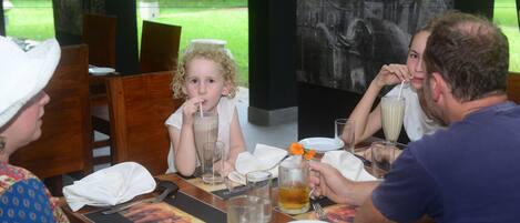 A group of people seated at a wooden table with a menu, glasses, and a pitcher of tea.