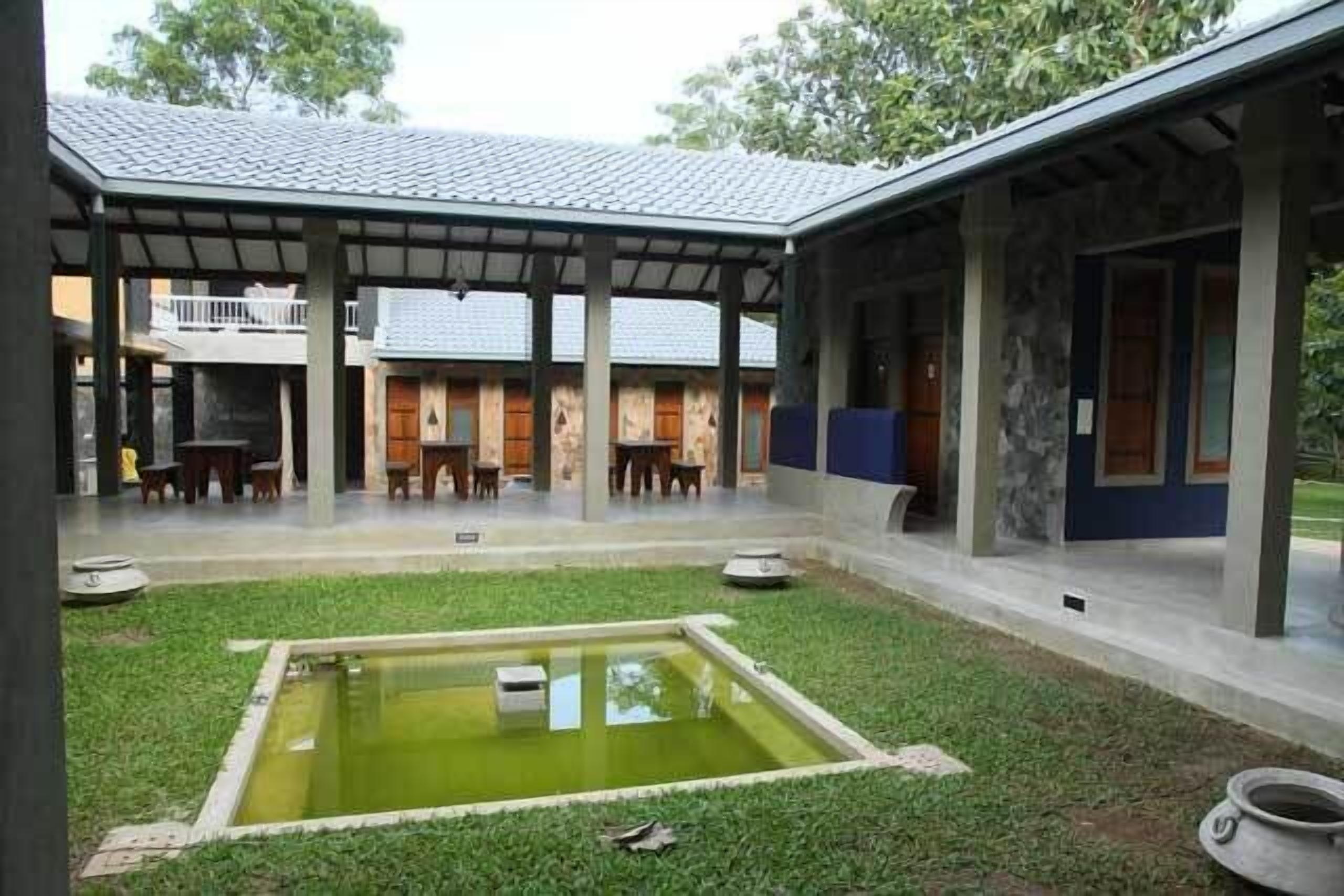 Ein Innenhof mit kleinem Pool, überdachter Sitzgelegenheit und Steinmauern.