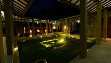 A covered outdoor area with a pool, stone walls, and wooden beams.