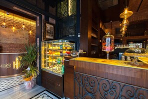 A bar area with a wooden counter, a glass display case with bottles, and a potted plant. - Hotel Pera Parma (Istanbul)