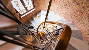 A spiral staircase with a brick wall and a decorative metal railing. - Hotel Pera Parma (Istanbul)