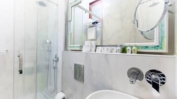 A modern bathroom with a glass-enclosed shower, a white sink, and a mirror above the sink.