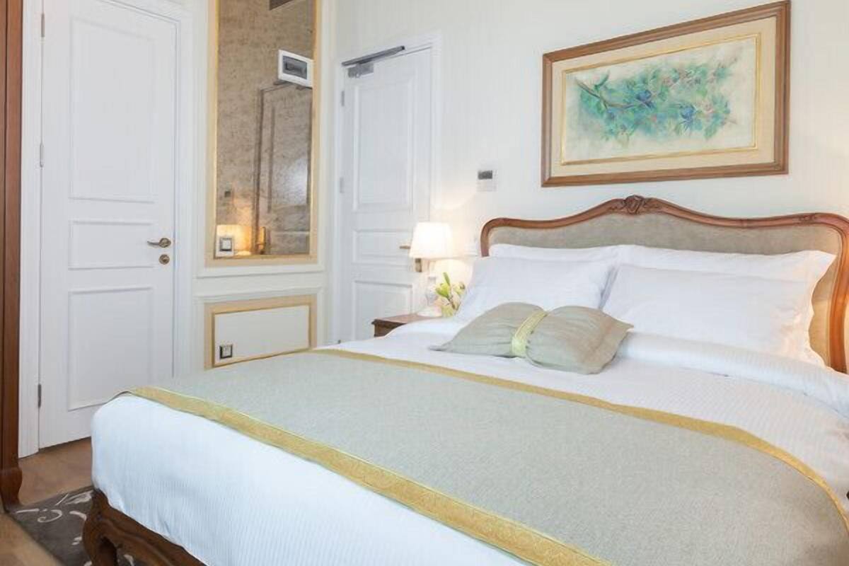 Un dormitorio con una cama, cabecera de madera, un cuadro en la pared y una puerta con espejo.