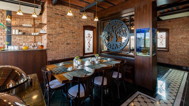 A restaurant with a brick wall, wooden ceiling beams, hanging pendant lights, a large decorative cut-out, and a fish tank. - Hotel Pera Parma (Istanbul)