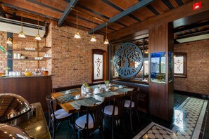 Un restaurante con pared de ladrillo, vigas de madera en el techo, lámparas colgantes y un gran adorno recortado, además de un acuario.