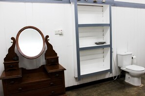 A bathroom with a wooden vanity, a mirror, a shelf, and a toilet. - City Hub Lagoon (Negombo)