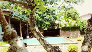 A swimming pool surrounded by trees and a brick wall. - City Hub Lagoon (Negombo)