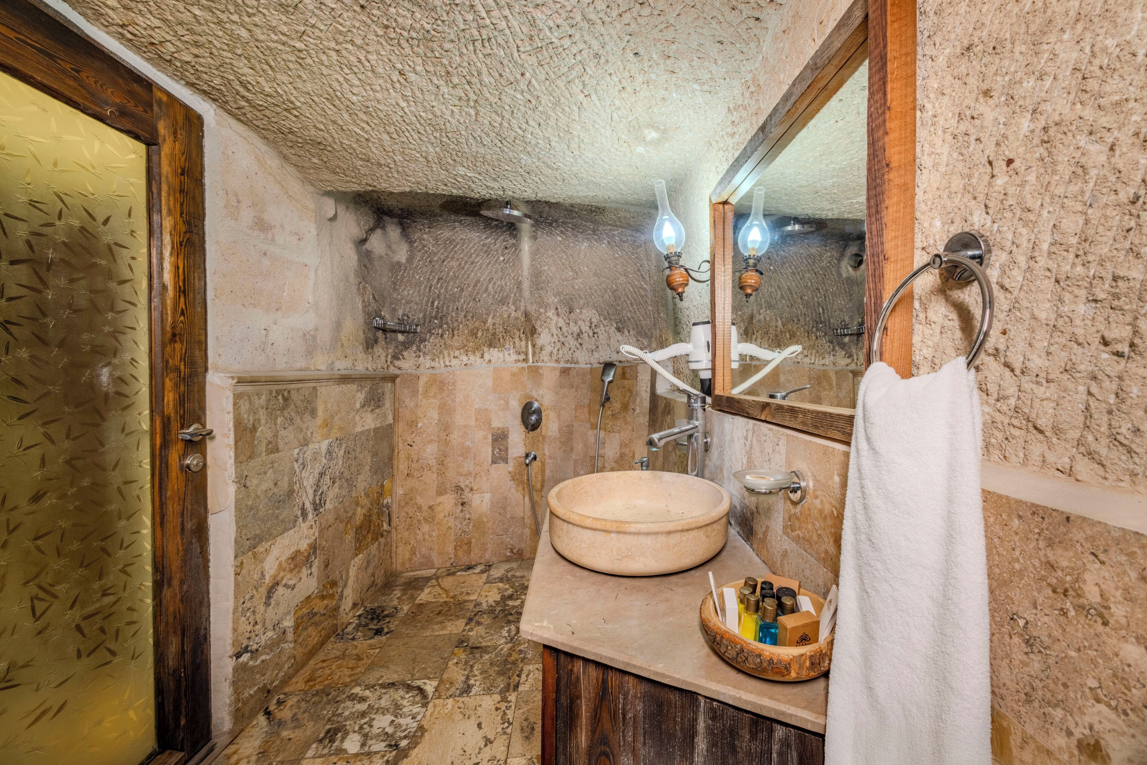 A bathroom with a stone sink, a wooden vanity, a mirror, and a towel rack.