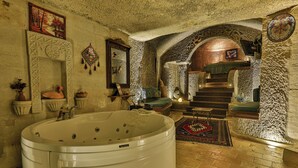 Un cuarto de spa con una bañera grande, paredes de piedra y una escalera que lleva a un nivel superior.