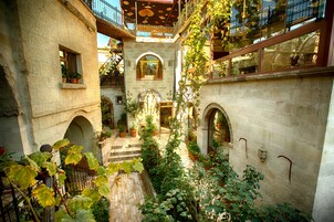 Un patio con paredes de piedra, puertas con arcos y plantas en macetas.