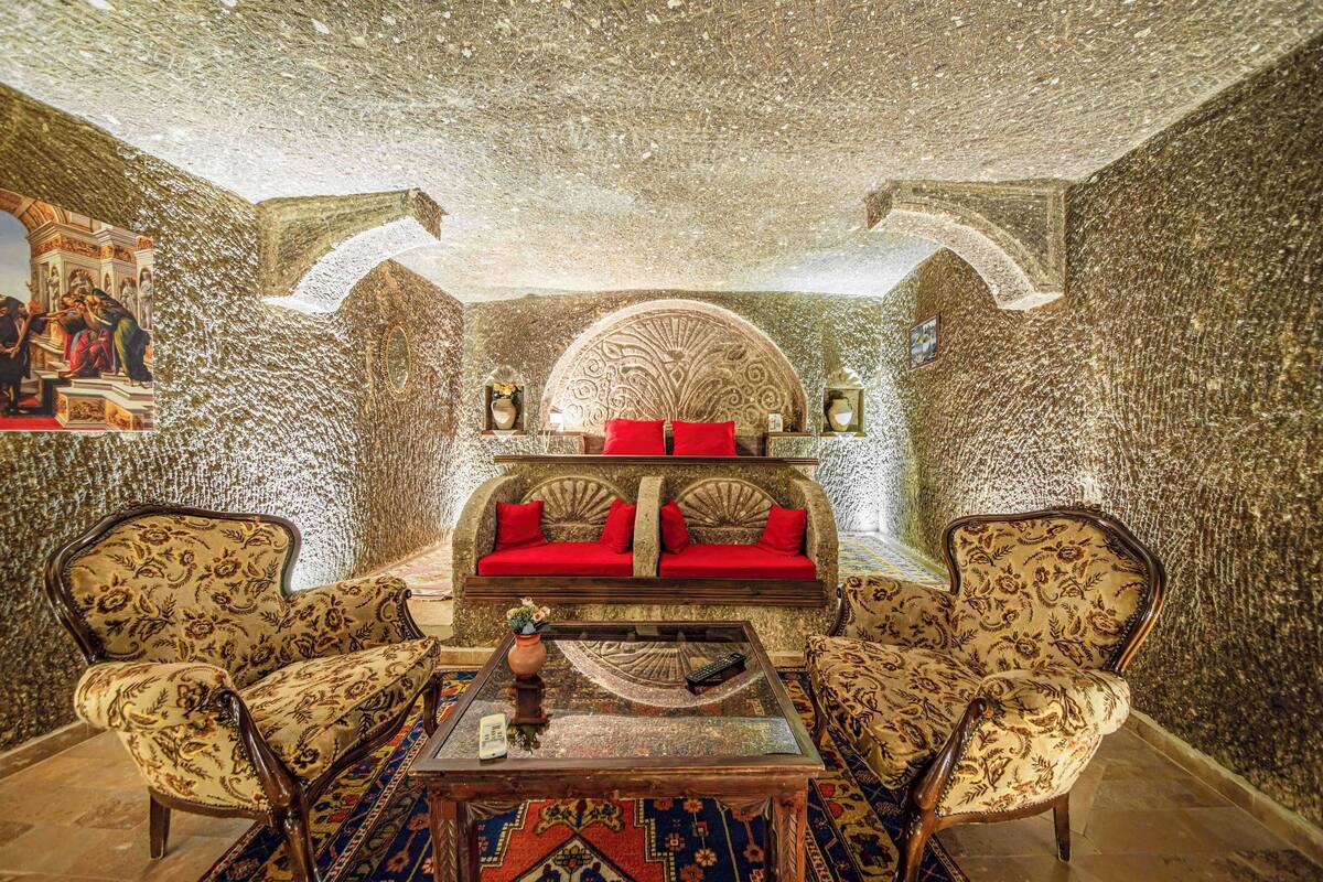 Um quarto com um sofá estampado, uma mesa de centro e duas poltronas.