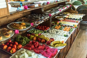 Un bufé con diversos alimentos, como frutas, pasteles y quesos.