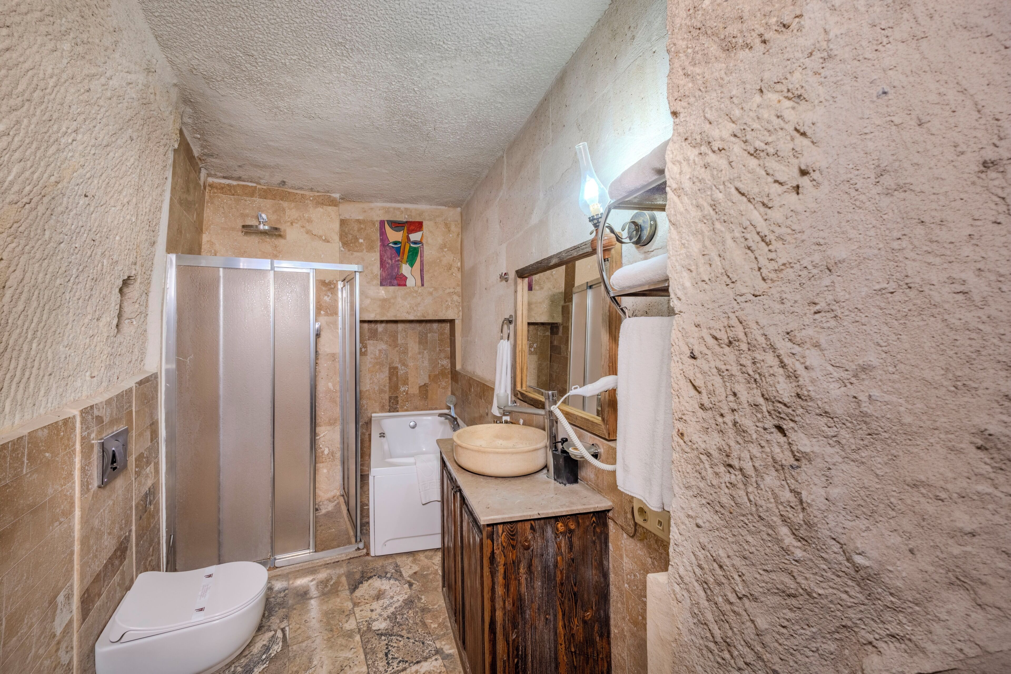 Un baño con ducha, inodoro, lavabo y un espejo con una toalla colgada.