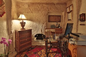 A rustic room with a wooden desk, a lamp, a telephone, and a computer. - Turkish Cave House (Ürgüp)