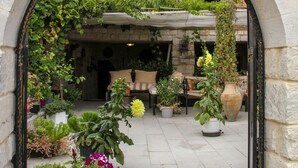 An arched entrance to a courtyard with potted plants, a bench, and a large vase. - Turkish Cave House (Ürgüp)