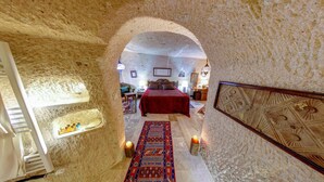 A room with a bed, a rug, and a decorative wall panel. - Turkish Cave House (Ürgüp)