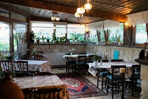 A cozy restaurant with wooden beams, potted plants, and tables set for dining. - Turkish Cave House (Ürgüp)
