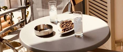 A small round table with a metal bowl, a glass of water, and a plate of food on a balcony.