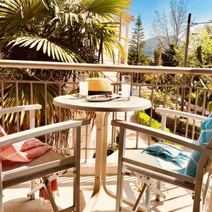 A balcony with a round table, two chairs, a wicker basket, and a glass of water. - George (Lefkada)