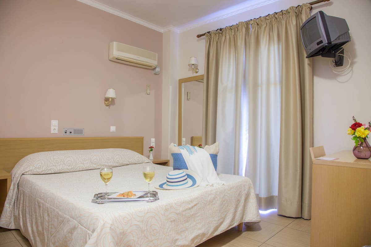 A hotel room with two beds, a desk, a television, and a mirror.