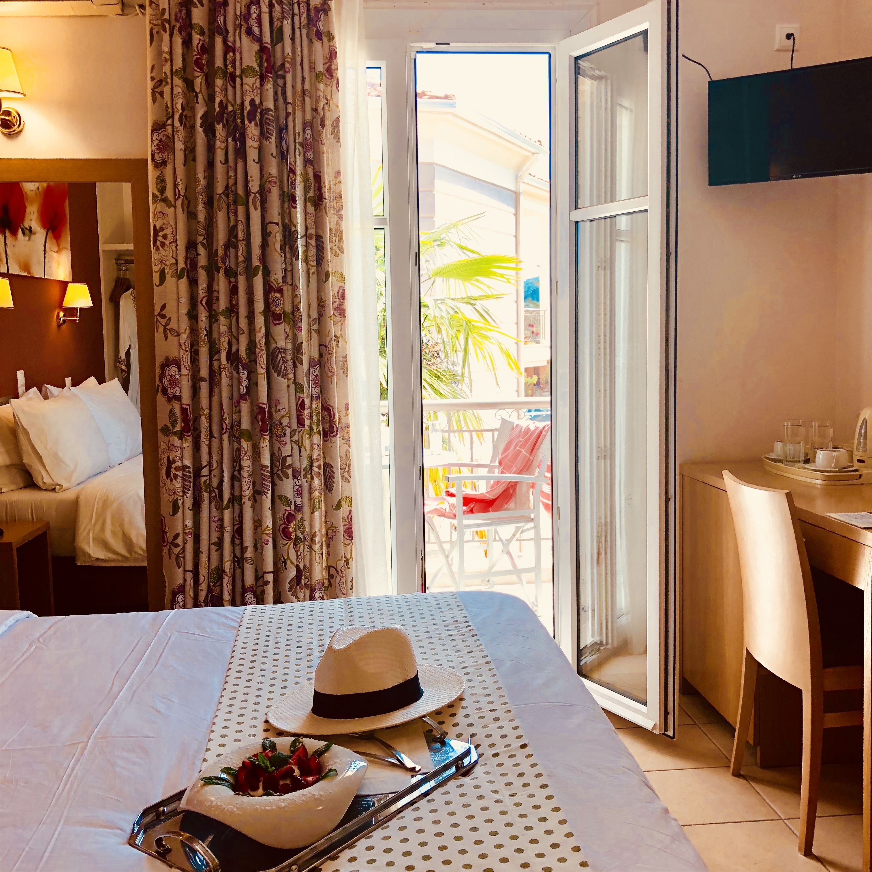 Hotelkamer met een bed, een eettafel, een stoel, een televisie en een balkon met een stoel en tafel.