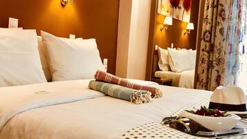 Una camera d'albergo con un letto rifatto, uno specchio e una finestra con tende a fiori.