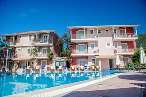 A hotel with a swimming pool, multiple balconies, and outdoor seating areas. - George (Lefkada)